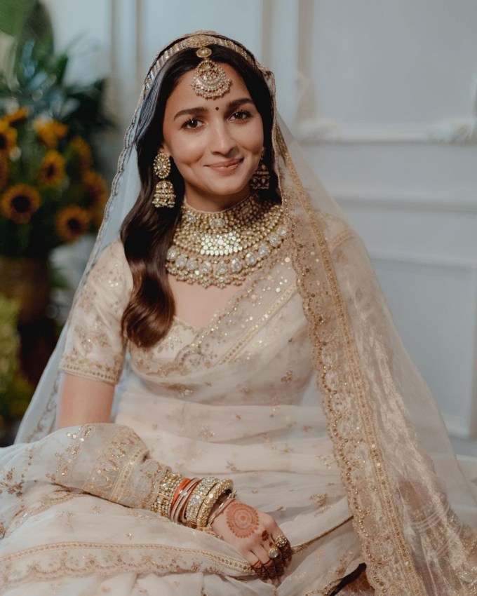 <strong>આલિયા ભટ્ટ મેરેજ લુક</strong><br>આલિયા ભટ્ટ અને રણબીર કપૂરના 14 એપ્રિલ 2022માં લગ્ન કર્યા હતા. આલિયા ભટ્ટે પણ મેરેજમાં ઓફ વ્હાઇટ ટ્યુશ ફેબ્રિક સાડી પહેરી હતી. આ ટ્રાન્સપરન્ટ ટ્યુશ ફેબ્રિક સાડી સાથે આલિયા ભટ્ટ હેવી ડાયમંડ નેકલેસ, ઈયરિંગ અને હાથમાં જ્વેલરી સાથે મેચિંગ બગડી અને કડા પહેર્યા હતા. તો માથામાં માંગ ટીકો અને શિશ ફુલ સાથે ઓપન હેર સ્ટાઇલ સાથે કેરી કરી હતી. આ ઓફ વ્હાઇટ બ્રાઉડલ ડ્રેસમાં આલિયા ભટ્ટ કોઇ રાજકુમારી જેવી દેખાતી હતી. (Photo: Social Media)