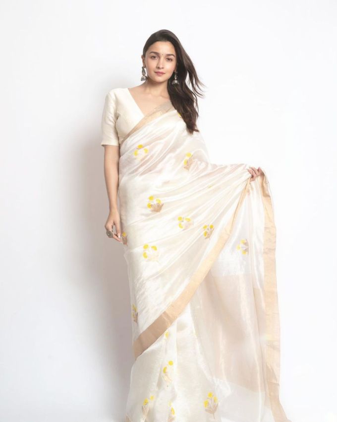 <strong>સફેદ સાડી આલિયા ભટ્ટ (Alia Bhatt White Saree) : </strong>જો તમને ફ્લોરલ સાડી ગમે છે, તો આલિયા ભટ્ટના સુંદર ફ્લોરલ સાડીના દેખાવમાંથી પ્રેરણા લઇ શકો છો. પીળા ફૂલો સફેદ સાડીના બેઝમાં છે. સાડીને મેચિંગ ફીટ બ્લાઉઝ સાથે જોડી દેવામાં આવે છે જેમાં હાફ સ્લીવ્ઝ અને વી શેપ નેકલાઇન હોય છે. વધારાની સ્ટાઇલ માટે ઓક્સિડાઇઝ્ડ ઝુમકા ઇયરિંગ્સ અને રિંગ્સ સાથે દેખાવને કમ્પ્લીટ કરે છે. આ સાથે તેણે સિમ્પલ મિનિમલ મેકઅપ કર્યો છે.