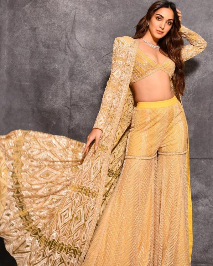 કિયારા અડવાણી : ફેશન મેજર ગોલ પુરા કરવા <a href="https://gujarati.indianexpress.com/about/kiara-advani/" data-type="URL" data-id="https://gujarati.indianexpress.com/about/kiara-advani/">કિયારા અડવાણી</a>એ અદભૂત યેલો ટ્રેડિશનલ આઉટફિટમાં જોવા મળી છે, તેના થ્રી-પીસના દાગીનામાં ડીપ નેક બ્લાઉઝ, પહોળી પેન્ટ અને ફ્લોય ફુલ સ્લીવ કેપ દર્શાવવામાં આવી હતી. તેના લુકને એક્સેસરાઇઝ કરવા માટે અભિનેત્રીએ એક નાજુક નેકપીસ અને સ્ટડ ઇયરિંગ્સ પસંદ કર્યા છે જેમાં પરફેક્ટ સ્પાર્કલ ઉમેરવામાં આવ્યું અને આખા આઉટફિટને ડ્રિમી ટચ આપી છે, અભિનેત્રીએ તેના સોફ્ટ વેવી અને નીચે ઢળતા  રાખ્યા અને ન્યૂડ લિપસ્ટિક, કાજલ સાથે લુક કંપ્લીટ કર્યો છે. આ કિયારા પ્રેરિત દિવાળી આઉટફિટ આ તહેવારોની સિઝનમાં તમારા આઉટફિટમાં વાઇબ્રન્ટ ટચ ઉમેરવા માટે યોગ્ય છે. 