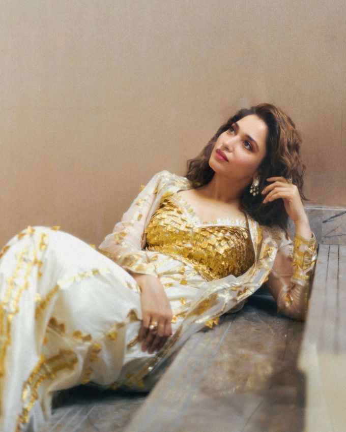 <strong>તમન્ના ભાટિયા ટ્રેડિશનલ લુક :</strong> તમન્ના ભાટિયાના આ યુનિક ટ્રેડિશનલ લુકમાં તેણે ઓફ વાઈટ અને ગોલ્ડન સાઈન વાળા 2 પીસ આઉટફિટ પસંદ કર્યા છે, જેમાં લોન્ગ સ્લીવ જોવા મળે છે અને અને વી શેપ્ડ નેકલાઇન અને ગોલ્ડન વર્ક જોવા મળે છે.