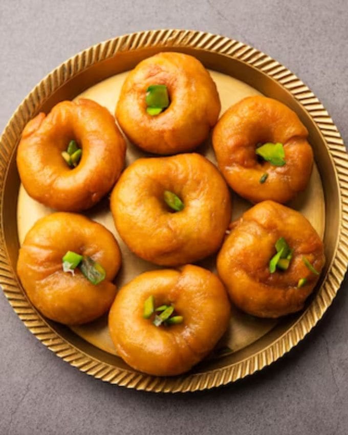 બાલુ શાહી (BaluShahi) મીઠાઈ <a href="https://gujarati.indianexpress.com/about/holi/" data-type="URL" data-id="https://gujarati.indianexpress.com/about/holi/">હોળી </a>ની ઉજવણીમાં મીઠાશ ઉમેરવા માટે બનાવવામાં આવે છે. બાલુ શાહીનો અનોખો સ્વાદ બાળકોની સાથે મોટા લોકોને પણ ગમે છે. તમને જણાવી દઈએ કે બાલુશાહી એક ટ્રેડિશનલ ભારતીય મીઠાઈ છે, જે તેના ખાસ મીઠા અને કરકરા સ્વાદ માટે જાણીતી છે. બાલુશાહી લોટ, ઘી અને ખાંડમાંથી બનાવવામાં આવે છે, અને તેને તળવામાં આવે છે અને ખાંડની ચાસણીમાં બોળીને બનાવવામાં આવે છે, જે તેનો સ્વાદ વધુ સ્વાદિષ્ટ બનાવે છે. 