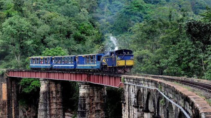<strong>નિલગીરી માઉન્ટેન રેલવે : Nilgiri Mountain Railway</strong><br>નિલગીરી માઉન્ટેન રેલવેમાં નીલગિરી પર્વતમાળાન સુંદર કુદરતી નજારો માણવાનો મોકો મળે છે. નિલગીરી માઉન્ટેન રેલવે તમિલનાડુમાં મેટ્ટપાલયમ અને ઉદગરમંડલમ વચ્ચેનું 46 કિમીનું અંતર 5 કલાકમાં પુરુ કરે છે. 16 સુરંગ અને 250 પુલો પરથી પસાર થતી આ ટ્રેન ચાના બગીચા માટે પ્રસિદ્ધ કુન્નુર શહેરમાંથી પસાર થયા છે. મેટ્ટપાલયમ કલ્લાર એડ્ડરલી કુન્નુર, વેલિંગ્ટન, કેટી રૂટ પર દોડતી નિલગીરી માઉન્ટેન રેલવે ટ્રેન પર યુનેસ્કોની હેરિટેજ યાદીમાં સામેલ છે. (Photo: Social Media)