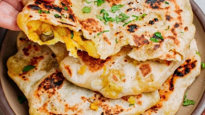 <strong>આલુ નાન (Aloo Naan) – રેન્ક 26 | રેટિંગ 4.4</strong><br>આલુ નાન એ નાનનું મસાલેદાર વર્ઝન છે, જે મસાલાવાળા બટાકાના ભરણથી ભરેલું છે. તે તંદૂરમાં પણ શેકવામાં આવે છે અને માખણથી મિક્સ કરવામાં આવે છે. આ બટાકાથી ભરેલું નાન દરેક પંજાબી ઢાબામાં મુખ્ય વાનગી છે. તે રાયતા, છોલે અથવા દાળ મખાણી સાથે પીરસવામાં આવે છે. (Photo Source: Unsplash)